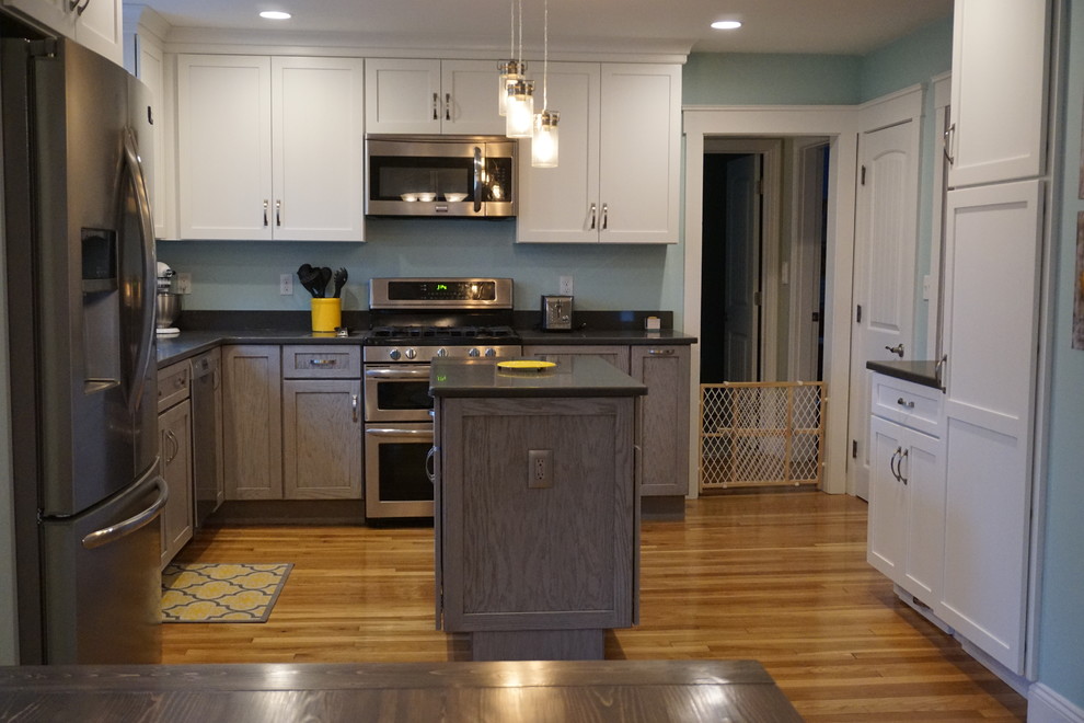 Inspiration for a mid-sized transitional u-shaped medium tone wood floor eat-in kitchen remodel in Boston with an undermount sink, shaker cabinets, gray cabinets, quartz countertops, black backsplash, stainless steel appliances and an island