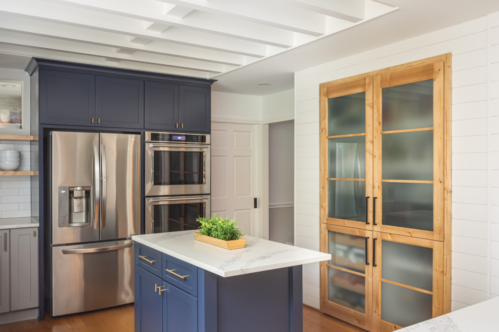 Example of a mid-sized transitional u-shaped medium tone wood floor and brown floor open concept kitchen design in Raleigh with an undermount sink, recessed-panel cabinets, blue cabinets, quartzite countertops, white backsplash, subway tile backsplash, stainless steel appliances, an island and white countertops