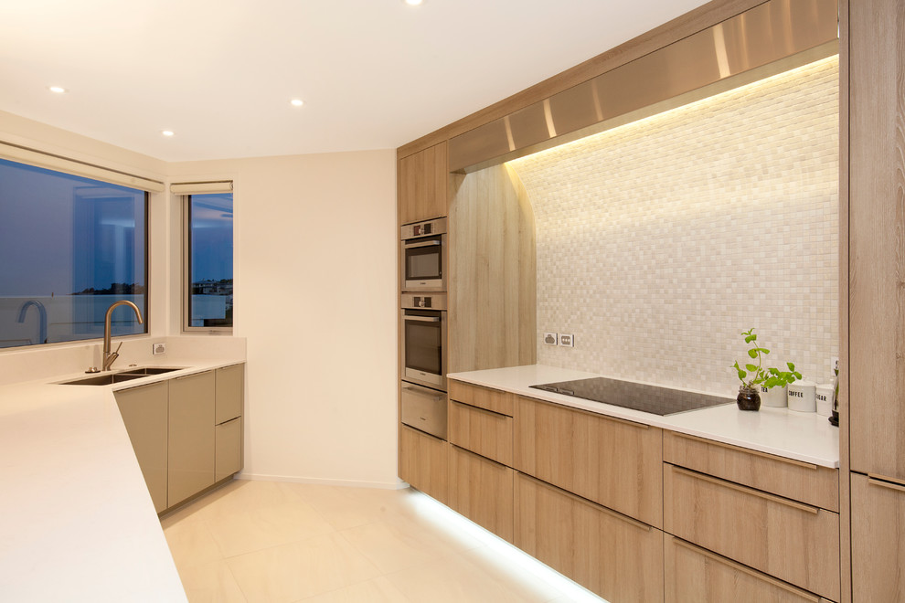 Photo of a mid-sized contemporary galley eat-in kitchen in Christchurch with light wood cabinets, white splashback, mosaic tile splashback, an undermount sink, quartz benchtops, stainless steel appliances, ceramic floors, with island, beige floor and white benchtop.