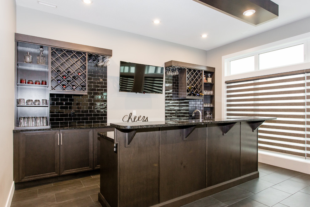Mid-sized contemporary single-wall wet bar in Calgary with an undermount sink, recessed-panel cabinets, grey cabinets, granite benchtops, black splashback, ceramic splashback, ceramic floors and grey floor.
