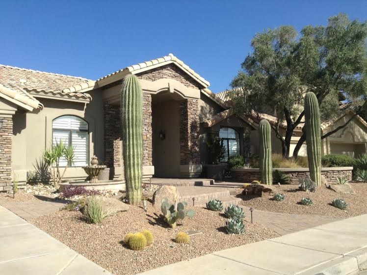 This is an example of a mid-sized modern front yard full sun xeriscape for winter in Phoenix with natural stone pavers.