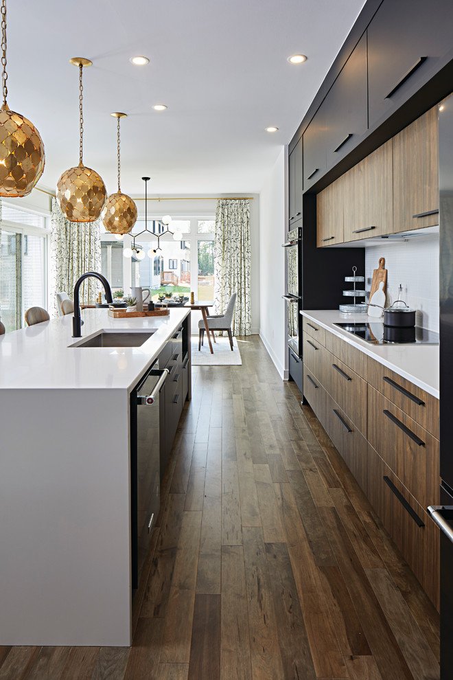 Photo of a mid-sized modern l-shaped eat-in kitchen in Ottawa with an undermount sink, flat-panel cabinets, black cabinets, granite benchtops, grey splashback, ceramic splashback, stainless steel appliances, dark hardwood floors, with island and brown floor.