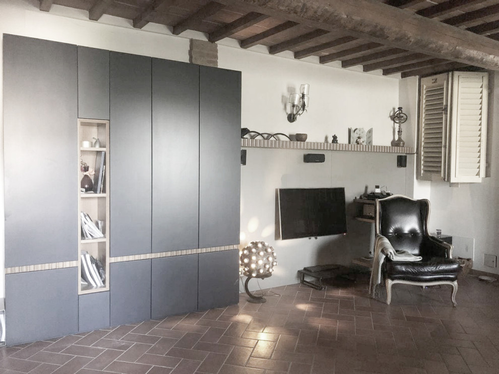 フィレンツェにある高級な小さな地中海スタイルのおしゃれなLDK (ベージュの壁、テラコッタタイルの床、暖炉なし、壁掛け型テレビ、茶色い床、表し梁) の写真
