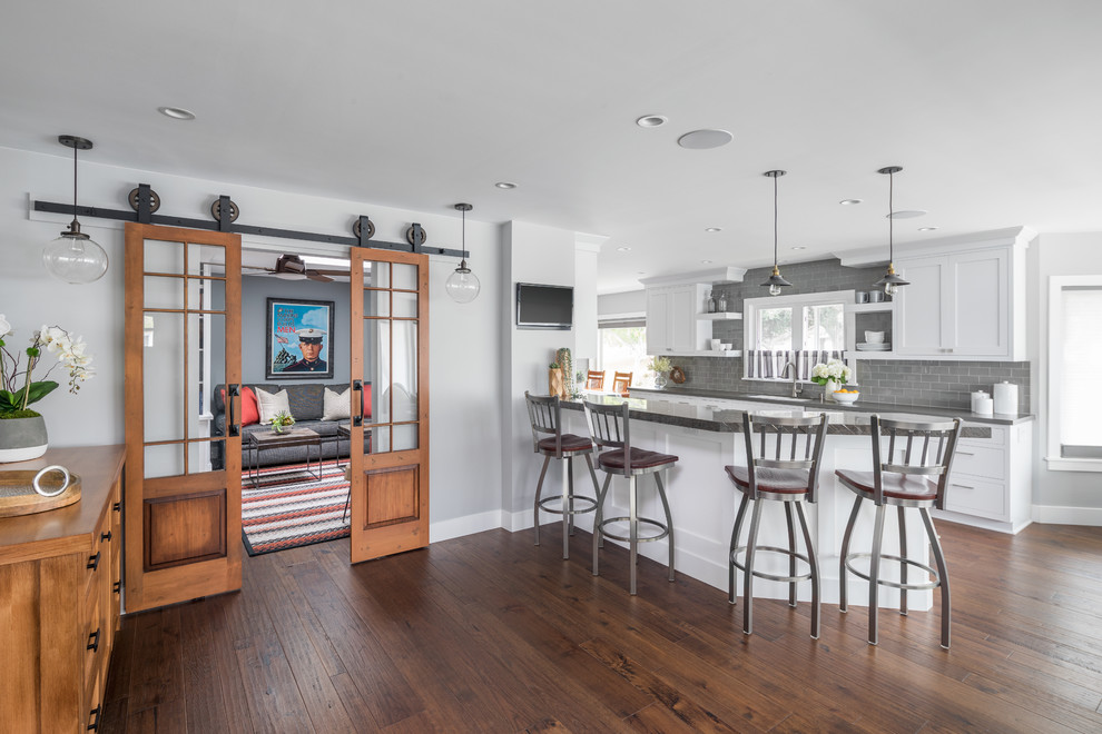 Design ideas for a transitional u-shaped kitchen in Orange County with shaker cabinets, white cabinets, grey splashback, subway tile splashback, dark hardwood floors, a peninsula, brown floor and grey benchtop.