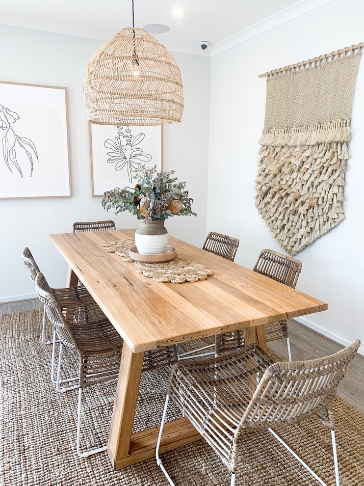 This is an example of a beach style dining room in Melbourne with white walls and laminate floors.