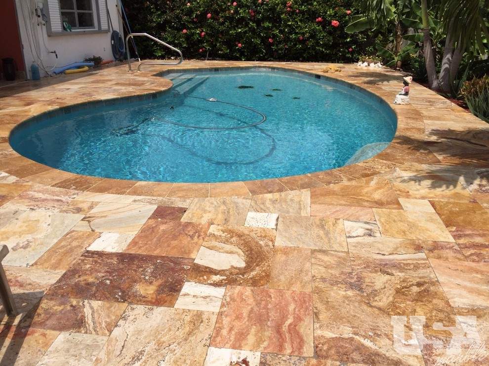 Photo of a large mediterranean backyard pool in Miami with natural stone pavers.