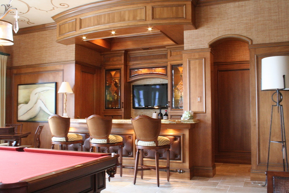This is an example of a large traditional single-wall seated home bar in Miami with glass-front cabinets, light wood cabinets, limestone benchtops, travertine floors and beige floor.
