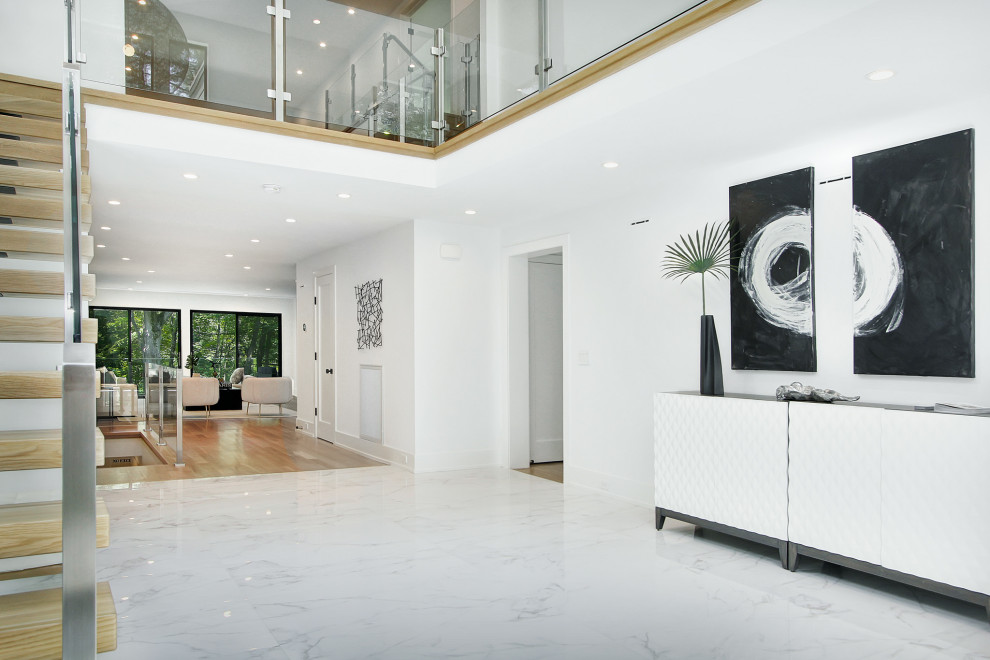 This is an example of a large contemporary foyer in New York with white walls, marble floors and white floor.