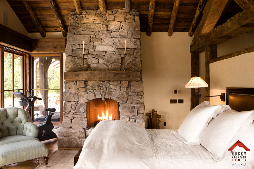 Design ideas for a mid-sized country bedroom in Other with a standard fireplace, a stone fireplace surround and beige walls.