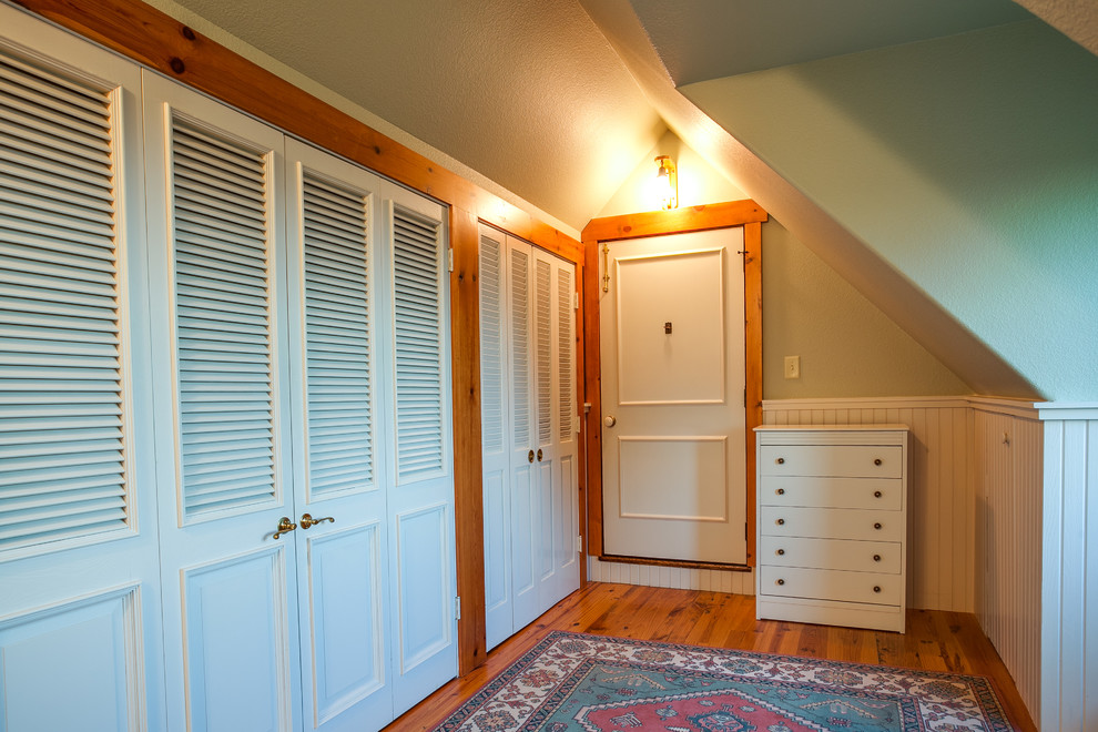 Photo of a mid-sized eclectic gender-neutral dressing room in Dallas with louvered cabinets, white cabinets and medium hardwood floors.