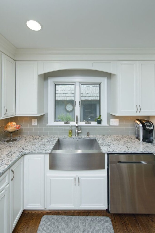 Inspiration for a transitional l-shaped medium tone wood floor eat-in kitchen remodel in Baltimore with a farmhouse sink, beaded inset cabinets, white cabinets, granite countertops, gray backsplash, glass tile backsplash, stainless steel appliances and an island