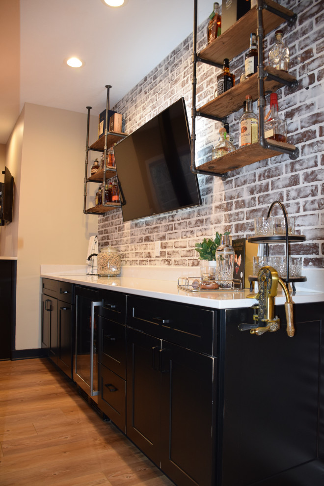 Inspiration for a large industrial galley wet bar in Other with an undermount sink, shaker cabinets, black cabinets, quartzite benchtops, red splashback, brick splashback, light hardwood floors, brown floor and white benchtop.