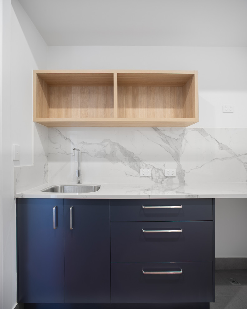 Inspiration for a modern single-wall separated utility room in Brisbane with a single-bowl sink, tile countertops, porcelain splashback, white walls, medium hardwood flooring and white worktops.
