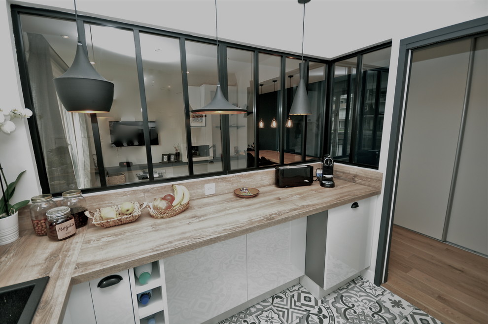 Cuisine?[Réalisation de cuisine With un évier encastré, un placard à porte plane, des portes de placard blanches, un plan de travail en bois, une crédence marron, un électroménager noir, carreaux de ciment au sol and un sol gris.]:[Réalisation de cuisines With un évier encastré, un placard à porte plane, des portes de placard blanches, un plan de travail en bois, une crédence marron, un électroménager noir, carreaux de ciment au sol and un sol gris.]
