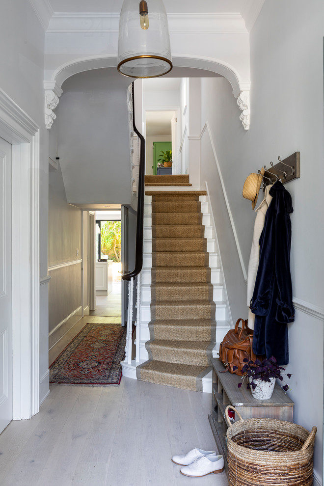 Design ideas for a mid-sized transitional wood u-shaped staircase in London with wood risers and wood railing.