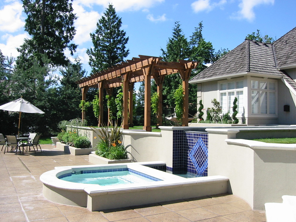 This is an example of a large arts and crafts backyard custom-shaped pool in Seattle with a hot tub and stamped concrete.