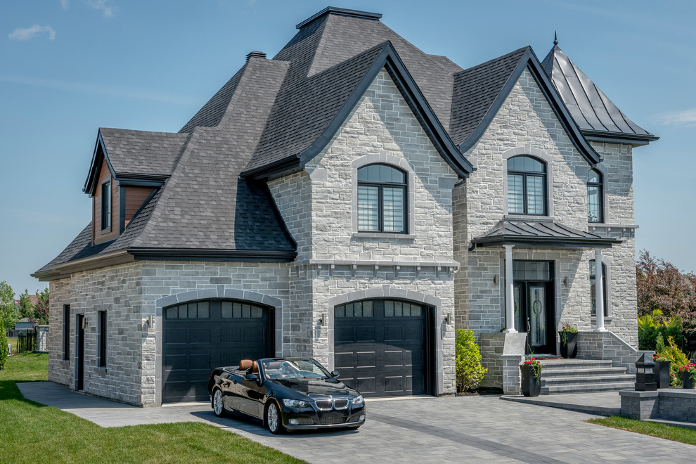 Inspiration for a traditional two-storey grey house exterior in Montreal with stone veneer and a gable roof.