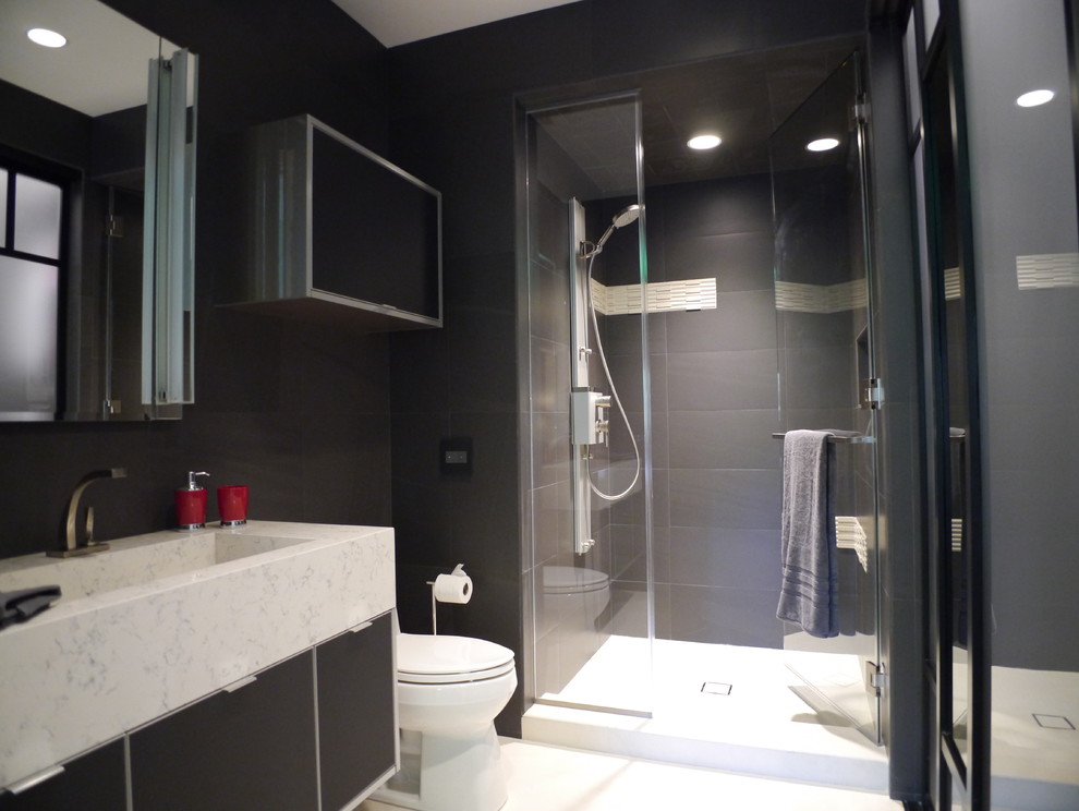 Design ideas for a mid-sized modern kids bathroom in Houston with a trough sink, black cabinets, engineered quartz benchtops, an open shower, a one-piece toilet, black tile, porcelain tile, black walls, porcelain floors and flat-panel cabinets.