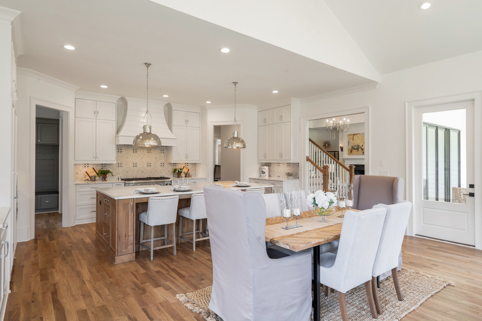 Inspiration for a country u-shaped eat-in kitchen in Atlanta with shaker cabinets, white cabinets, beige splashback, stainless steel appliances, medium hardwood floors, with island, brown floor and white benchtop.