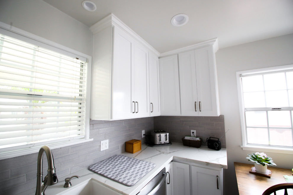 This is an example of a mid-sized transitional l-shaped eat-in kitchen in Los Angeles with an undermount sink, shaker cabinets, white cabinets, quartzite benchtops, grey splashback, subway tile splashback, stainless steel appliances, light hardwood floors, no island, grey floor and white benchtop.