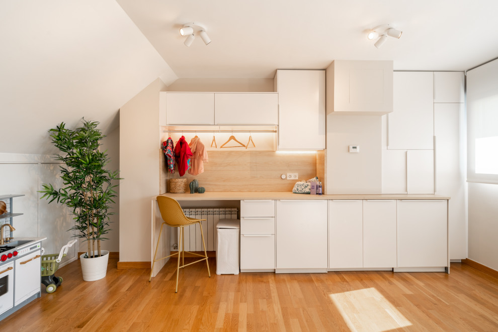 Medium sized scandinavian single-wall utility room in Other with flat-panel cabinets, white cabinets, wood worktops, brown splashback, wood splashback, white walls, laminate floors, an integrated washer and dryer, brown floors and brown worktops.