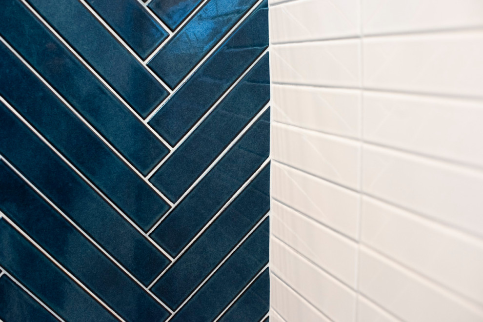 На фото: главная ванная комната среднего размера в стиле неоклассика (современная классика) с плоскими фасадами, фасадами цвета дерева среднего тона, душем в нише, унитазом-моноблоком, синей плиткой, керамической плиткой, белыми стенами, полом из керамогранита, врезной раковиной, столешницей из искусственного камня, белым полом, душем с раздвижными дверями, белой столешницей и тумбой под одну раковину с