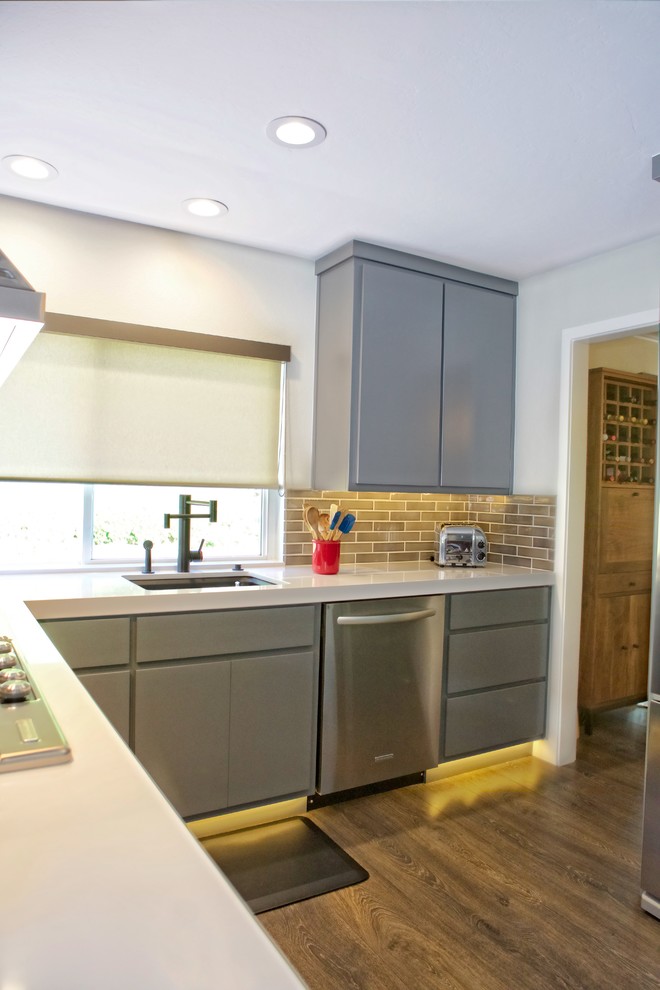 This is an example of a mid-sized modern separate kitchen in San Diego with an undermount sink, flat-panel cabinets, grey cabinets, quartz benchtops, grey splashback, ceramic splashback, stainless steel appliances and laminate floors.
