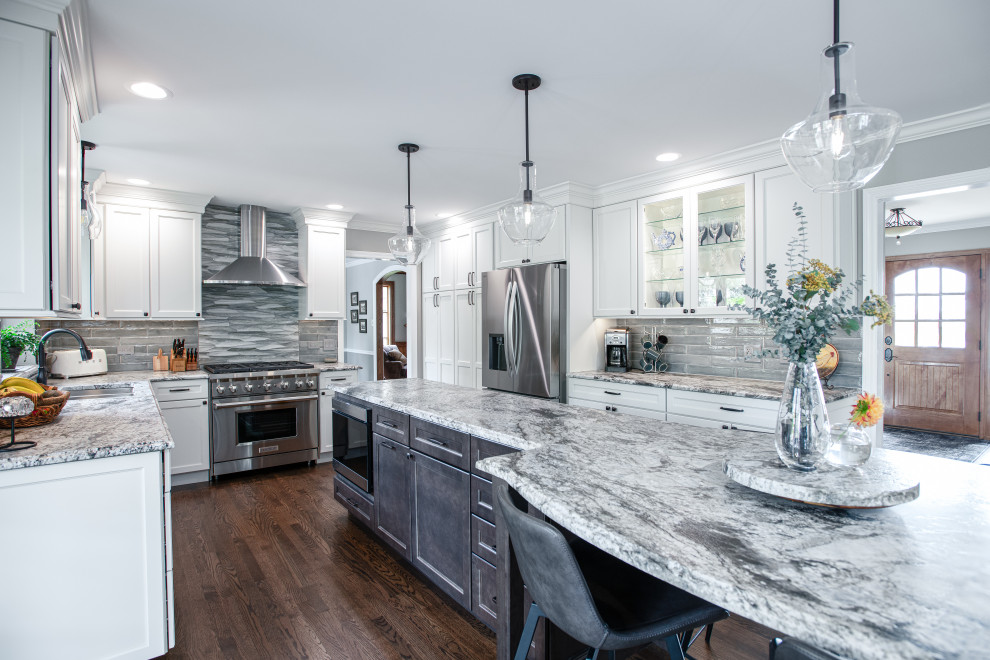 Inspiration for a mid-sized transitional u-shaped dark wood floor and brown floor open concept kitchen remodel in Chicago with a double-bowl sink, shaker cabinets, white cabinets, quartz countertops, blue backsplash, porcelain backsplash, stainless steel appliances, an island and gray countertops
