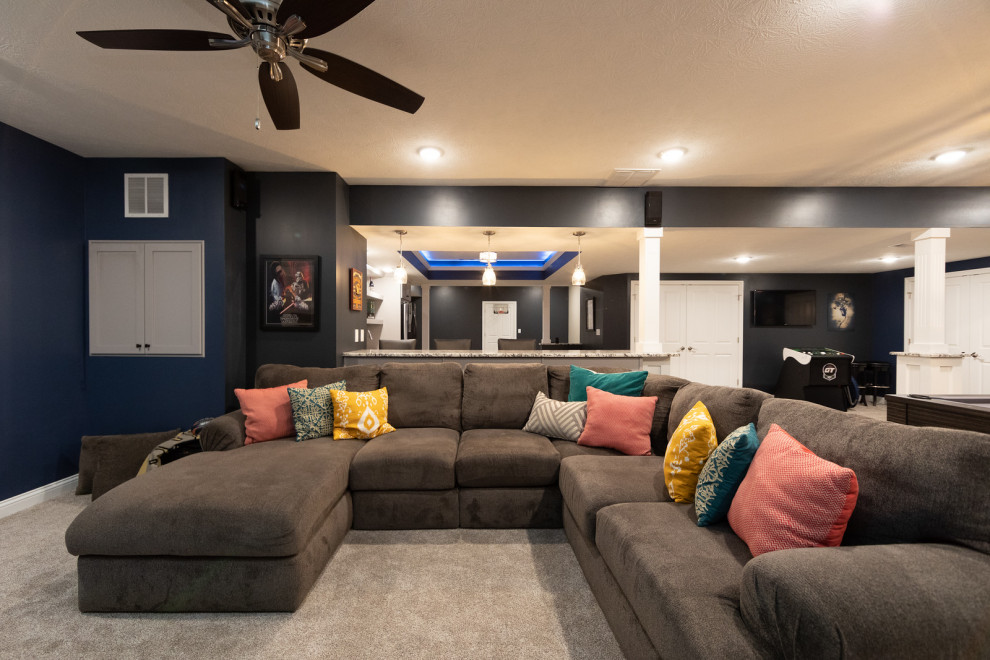 Photo of a large contemporary look-out basement in Other with blue walls, carpet, a standard fireplace, a tile fireplace surround and beige floor.
