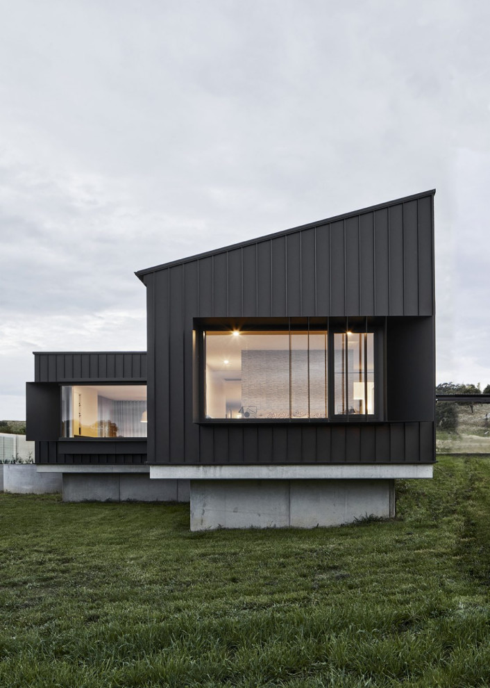 Inspiration for a large modern one-storey black house exterior in Other with a black roof.