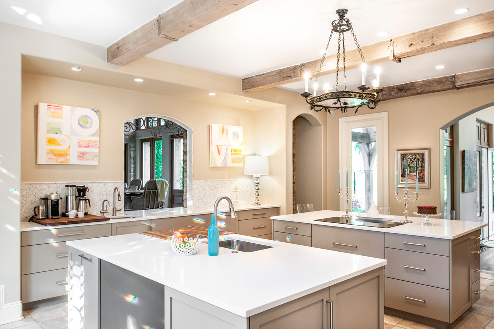 Example of a mid-sized transitional ceramic tile and brown floor enclosed kitchen design with an undermount sink, flat-panel cabinets, beige cabinets, quartzite countertops, white backsplash, ceramic backsplash, stainless steel appliances, two islands and white countertops
