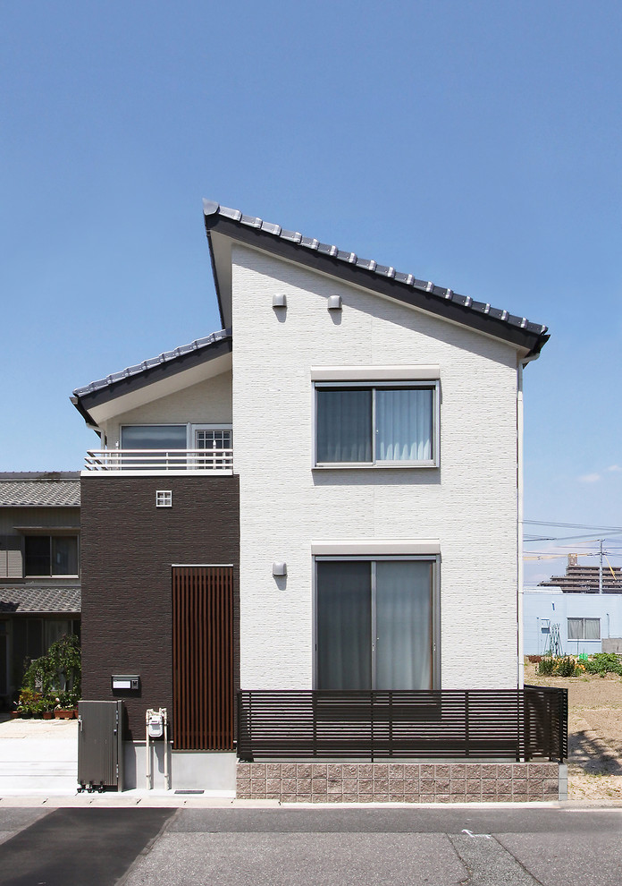 Photo of a contemporary two-storey white exterior in Nagoya with concrete fiberboard siding and a gable roof.