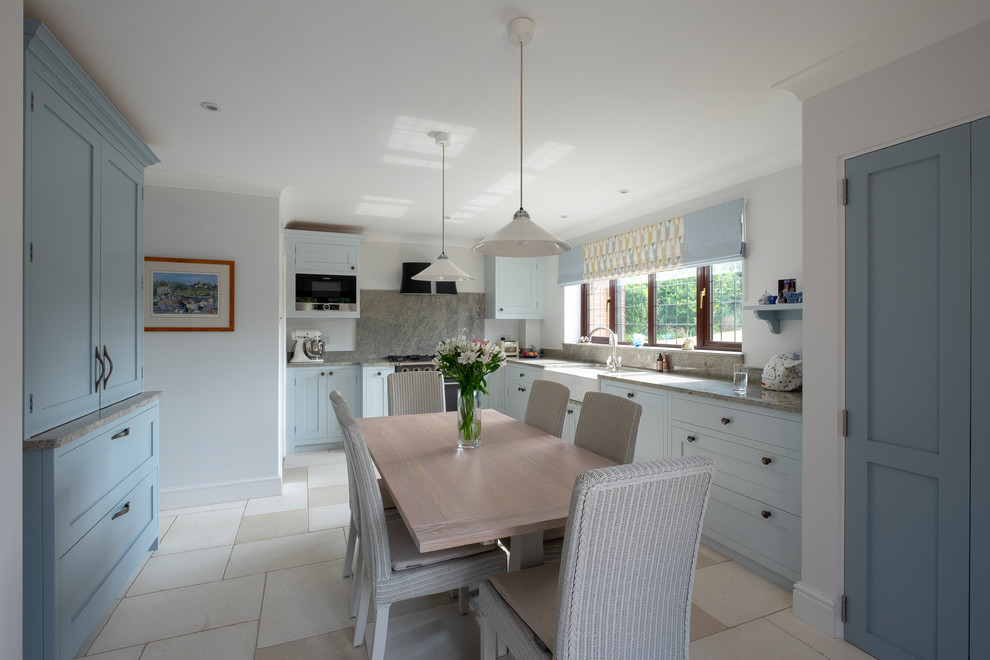 Mid-sized contemporary l-shaped separate kitchen in Hampshire with a farmhouse sink, shaker cabinets, blue cabinets, granite benchtops, multi-coloured splashback, stone slab splashback, black appliances, limestone floors, multi-coloured floor and multi-coloured benchtop.