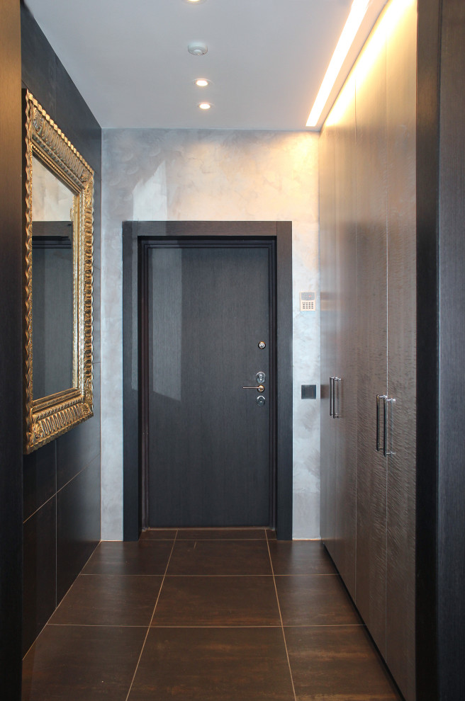 Ispirazione per un corridoio bohémian di medie dimensioni con pareti nere, pavimento in gres porcellanato, una porta singola, una porta in legno scuro e pavimento nero