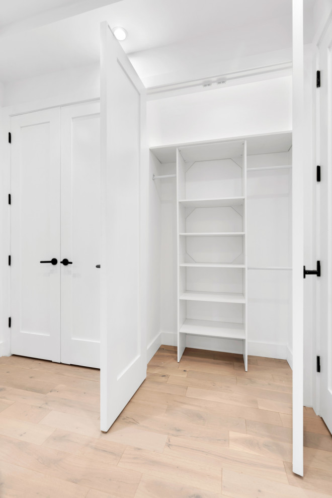 На фото: шкаф в нише среднего размера, унисекс в стиле ретро с плоскими фасадами, белыми фасадами и светлым паркетным полом с