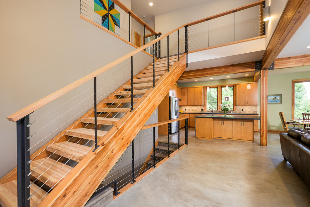 This is an example of a contemporary wood straight staircase in Seattle with open risers and cable railing.
