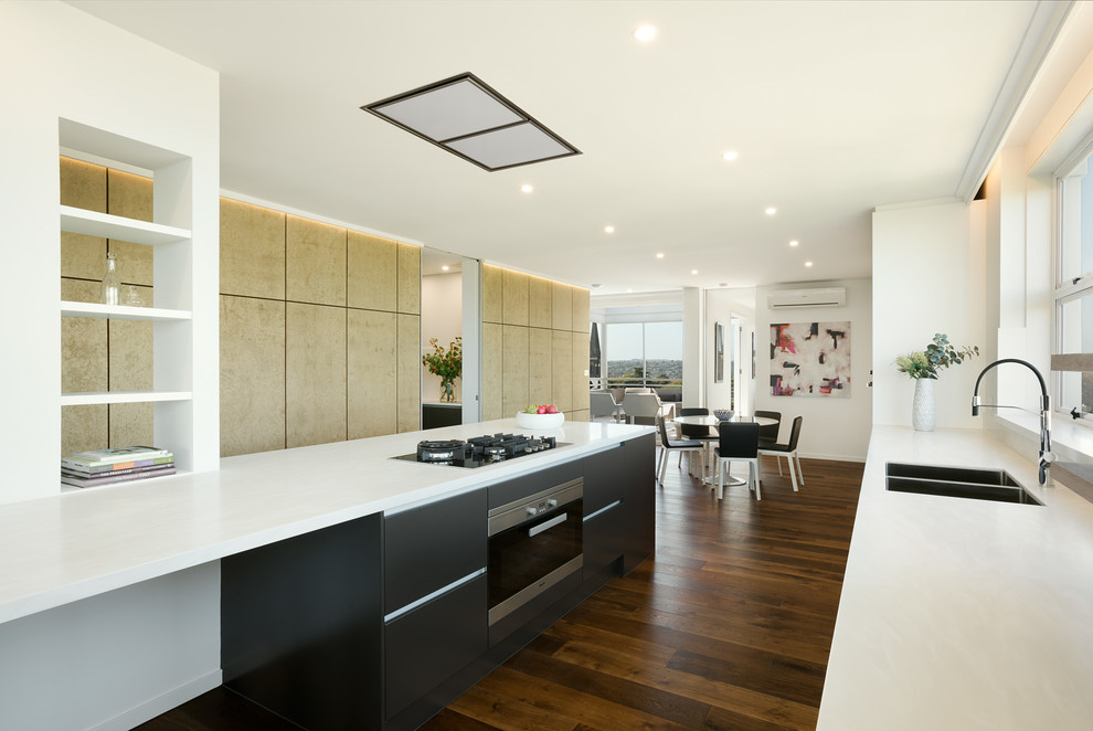 Contemporary kitchen in Melbourne with an undermount sink, flat-panel cabinets, grey cabinets, solid surface benchtops, white splashback, stainless steel appliances and medium hardwood floors.