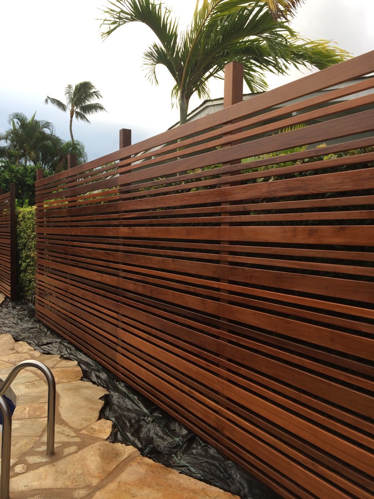 This is an example of a mid-sized tropical backyard full sun garden in Hawaii with natural stone pavers.