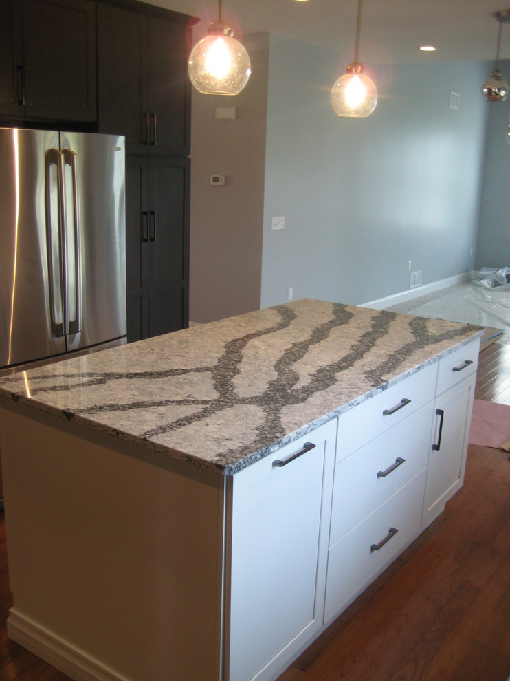 Example of a mid-sized transitional u-shaped medium tone wood floor and brown floor open concept kitchen design with an undermount sink, shaker cabinets, dark wood cabinets, quartz countertops, white backsplash, glass tile backsplash, stainless steel appliances, an island and white countertops