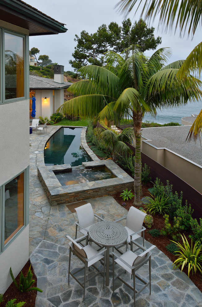 Small transitional backyard custom-shaped lap pool in San Diego with a hot tub and natural stone pavers.