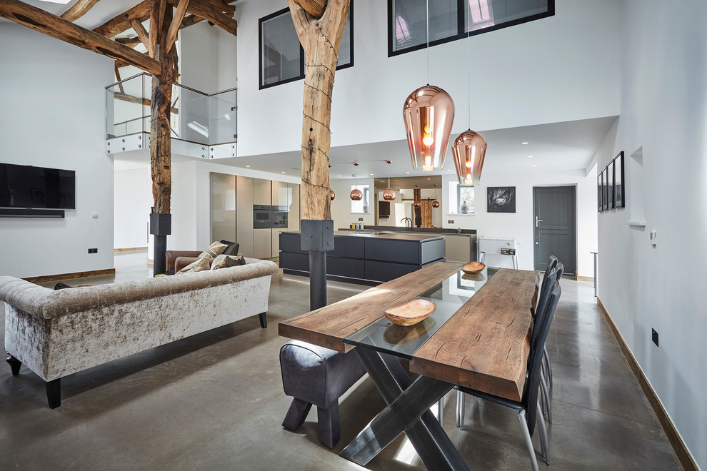 This is an example of a large contemporary l-shaped open plan kitchen in Other with a drop-in sink, flat-panel cabinets, black cabinets, quartz benchtops, multi-coloured splashback, mirror splashback, coloured appliances, concrete floors, with island, grey floor, black benchtop and exposed beam.