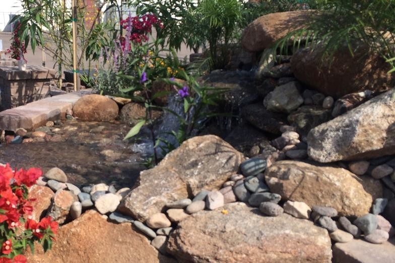 Large backyard full sun garden in Phoenix with a water feature and natural stone pavers.