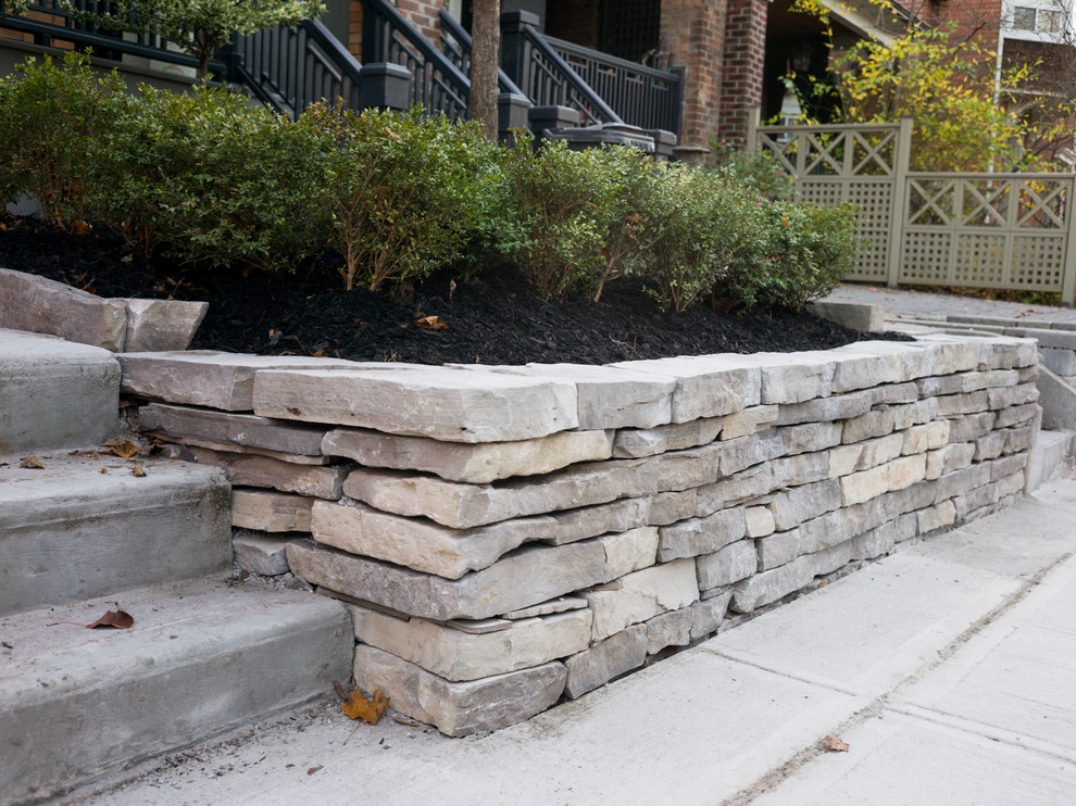 Inspiration for a small traditional front yard full sun driveway for fall in Toronto with a retaining wall and natural stone pavers.