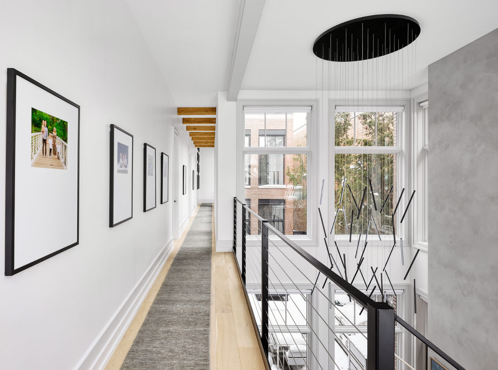 На фото: коридор в стиле модернизм с белыми стенами, светлым паркетным полом и балками на потолке с