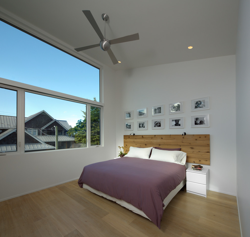 Photo of a modern bedroom in Vancouver with white walls and light hardwood floors.