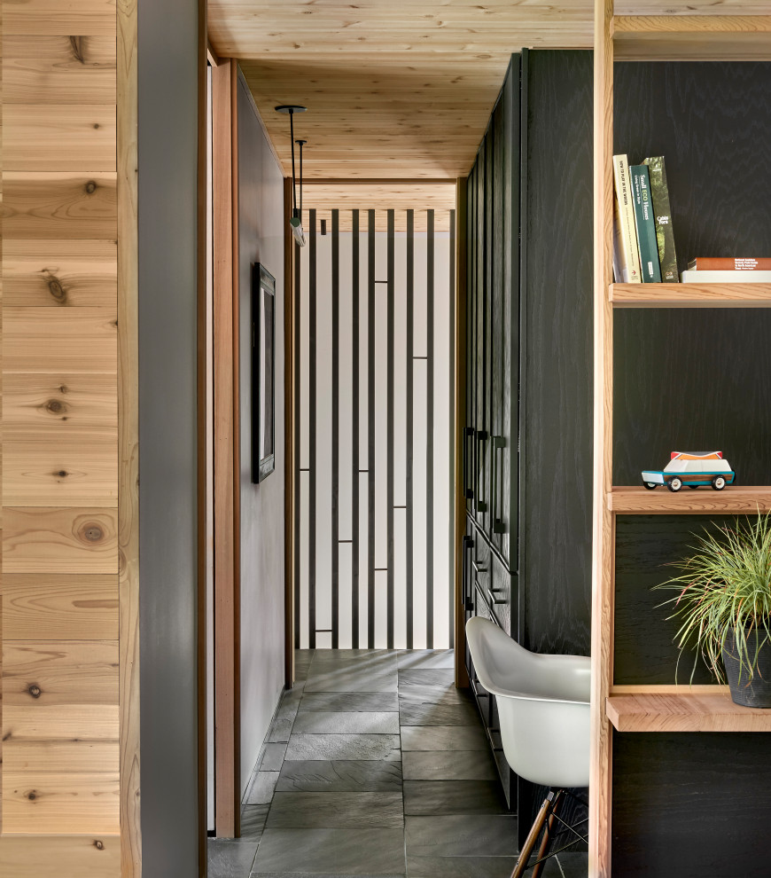 Photo of a mid-sized country hallway in Chicago with white walls, slate floors, black floor and wood walls.