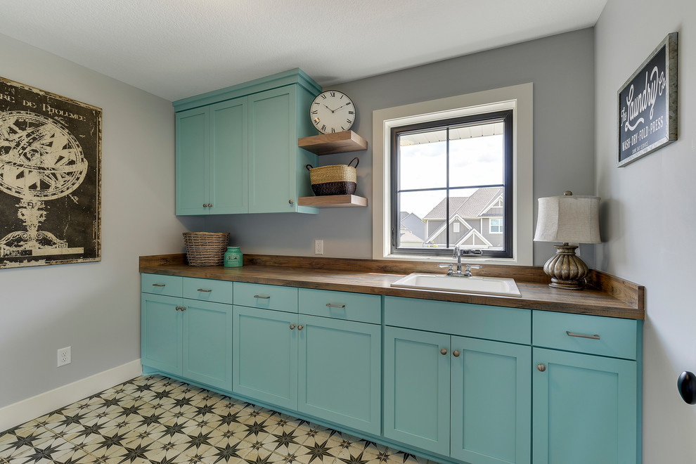 Design ideas for a mid-sized country galley dedicated laundry room in Minneapolis with a drop-in sink, flat-panel cabinets, turquoise cabinets, laminate benchtops, grey walls, porcelain floors, a side-by-side washer and dryer and multi-coloured floor.