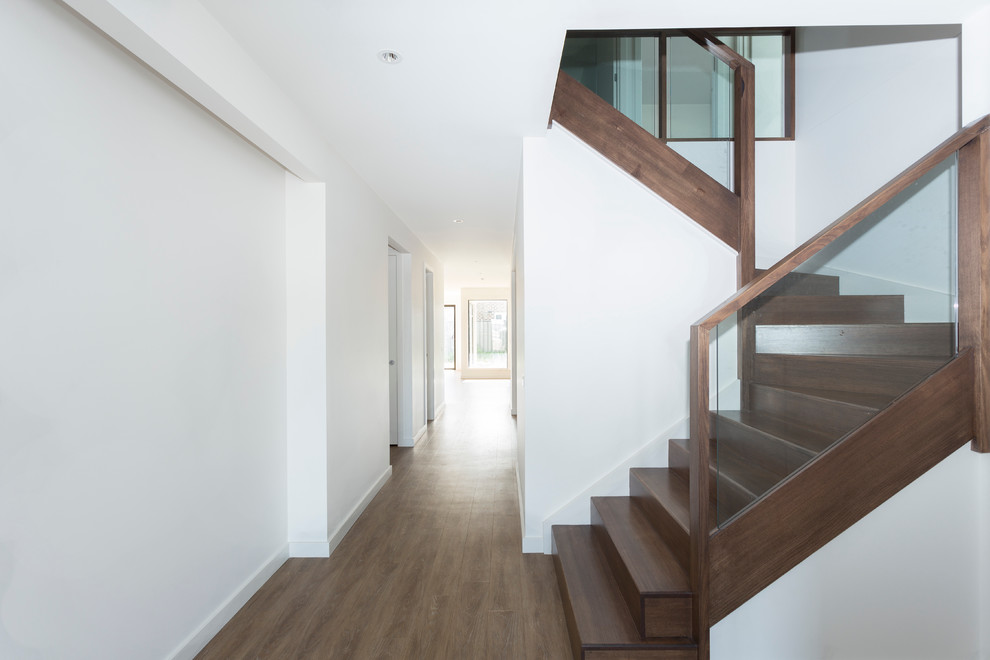 This is an example of a small contemporary wood u-shaped staircase in Melbourne with wood risers and wood railing.