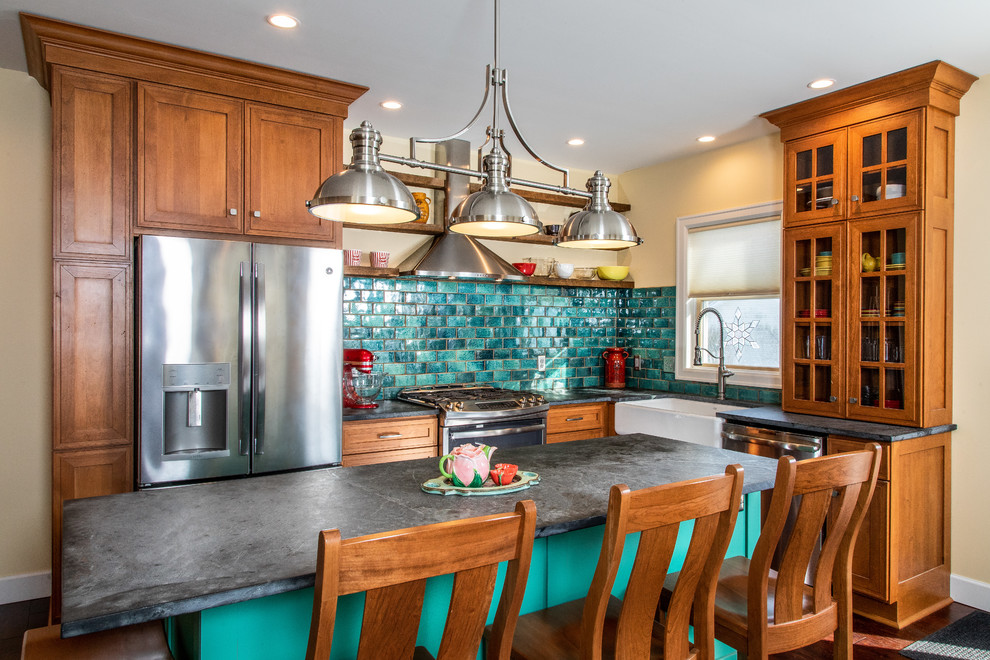 This is an example of a traditional l-shaped kitchen in Detroit with a farmhouse sink, medium wood cabinets, green splashback, stainless steel appliances, with island, black benchtop and soapstone benchtops.