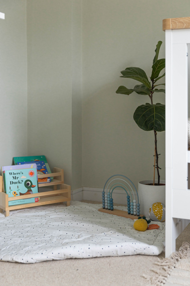 This is an example of a mid-sized scandinavian nursery for boys in Sussex with green walls, carpet and beige floor.